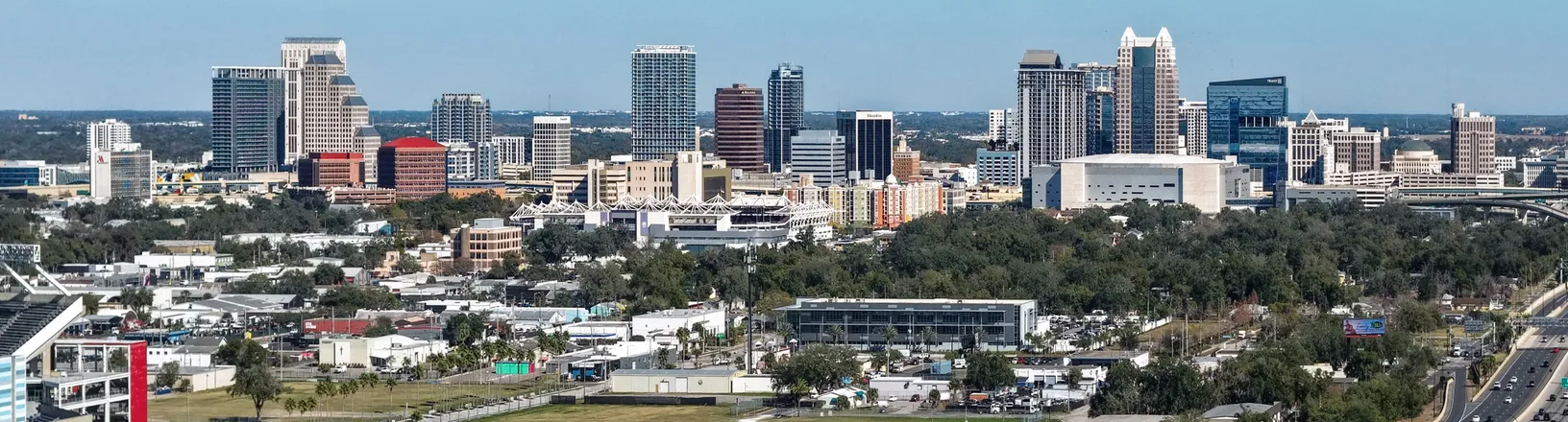 The downtown Orlando skyline on a clear day, with office towers behind low-rise neighbourhoods.